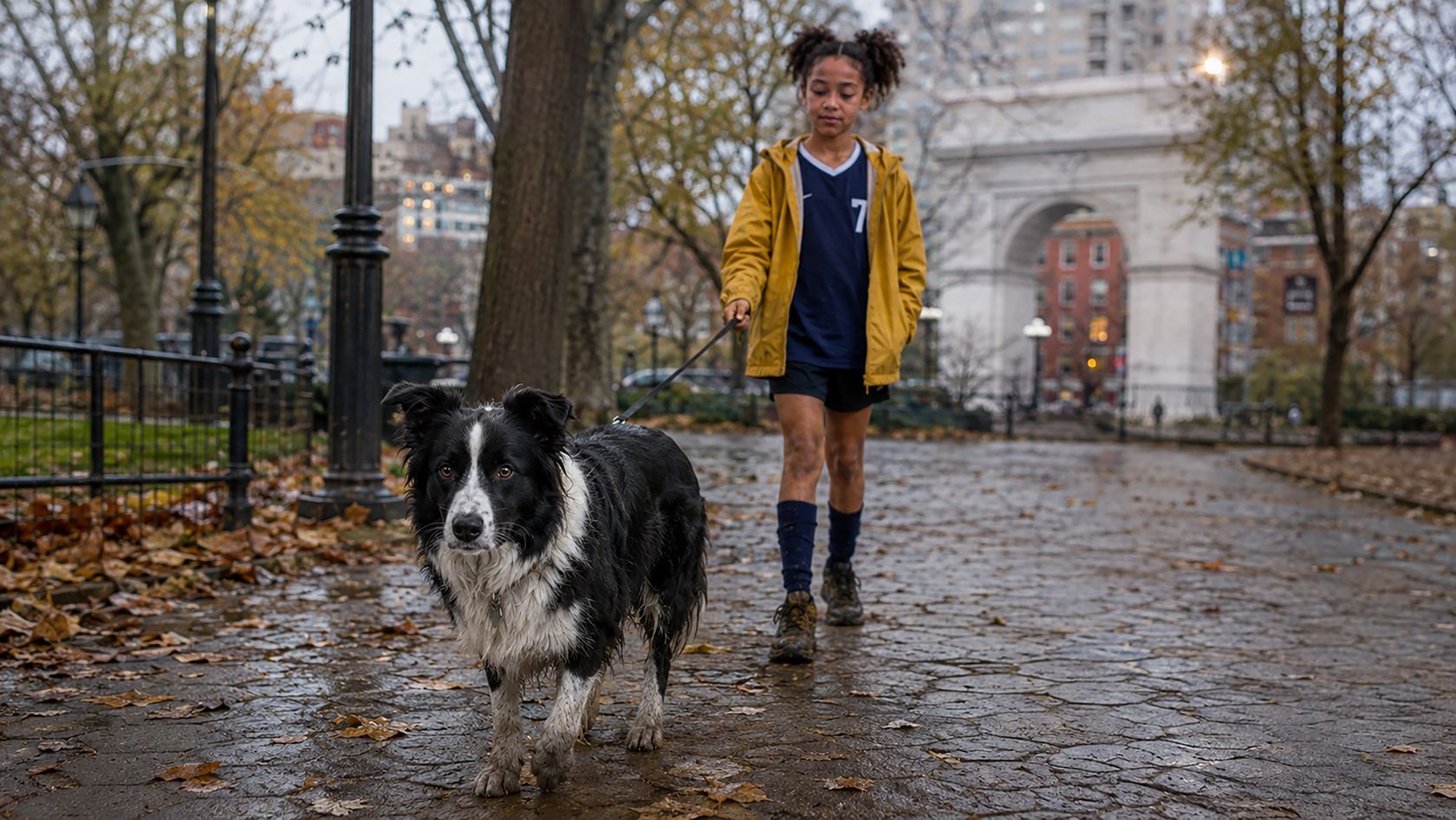 A child walking a dog on a rainy city street